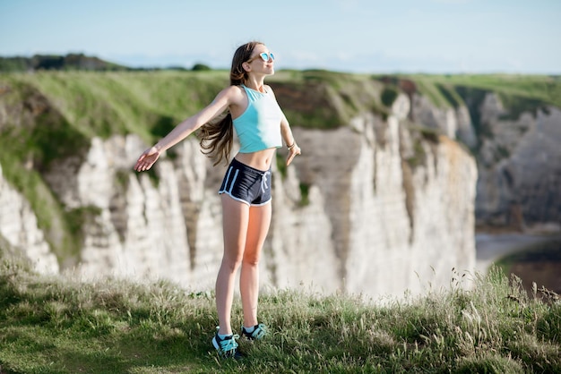 Mulher jovem em roupas esportivas nadando profundamente após o treinamento em pé no fundo da bela costa rochosa perto da cidade de Etretat, na França