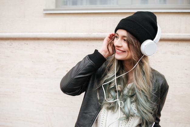 Mulher jovem em roupas quentes, ouvindo música na rua