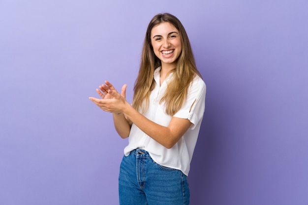 Mulher jovem em roxo isolado aplaudindo