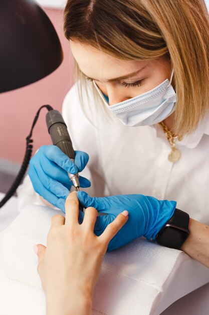 Mulher jovem em tratamento de manicure em salão de beleza