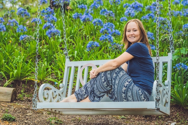 Mulher jovem em um balanço em um jardim de flores