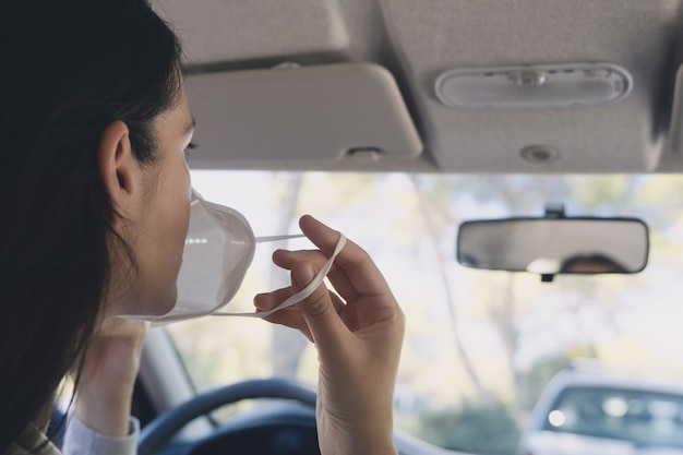 Foto mulher jovem em um carro usando uma máscara protetora durante a pandemia de covid-19