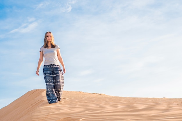 Mulher jovem em um deserto de areia radiante ao pôr do sol ou amanhecer