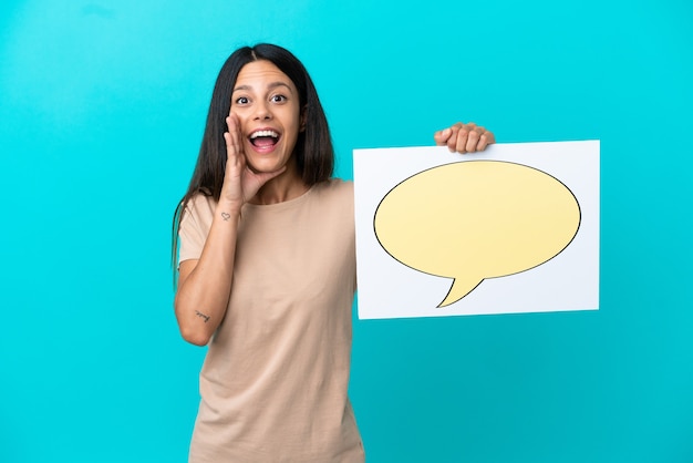 Mulher jovem em um fundo isolado segurando um cartaz com o ícone de um balão de fala e gritando