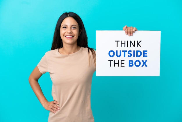 Mulher jovem em um fundo isolado segurando um cartaz com o texto Pense fora da caixa com uma expressão feliz