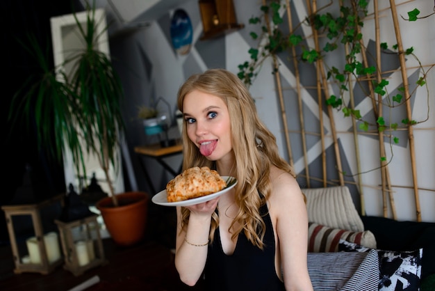 Mulher jovem em um macacão preto comendo croissants