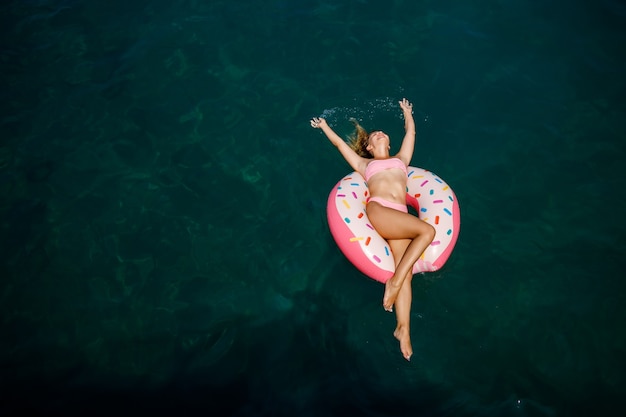 Mulher jovem em um maiô nada em um anel inflável no mar. Conceito de férias de verão.