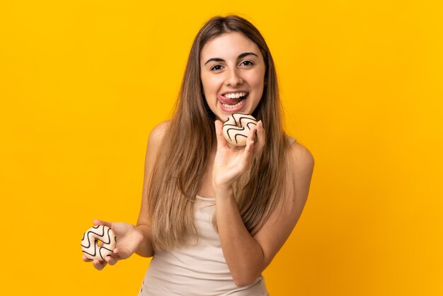 Mulher jovem em uma parede amarela isolada segurando um donut