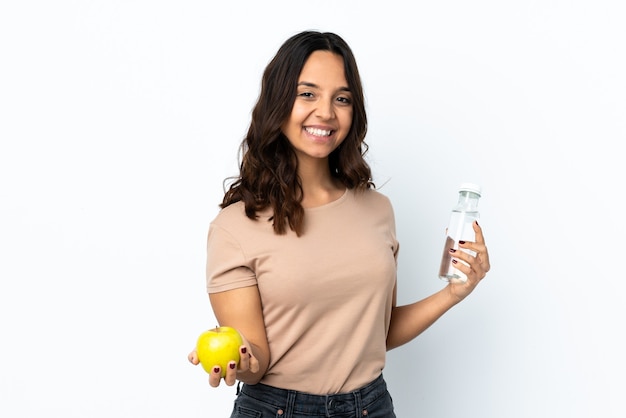 Mulher jovem em uma parede branca isolada com uma maçã e uma garrafa de água