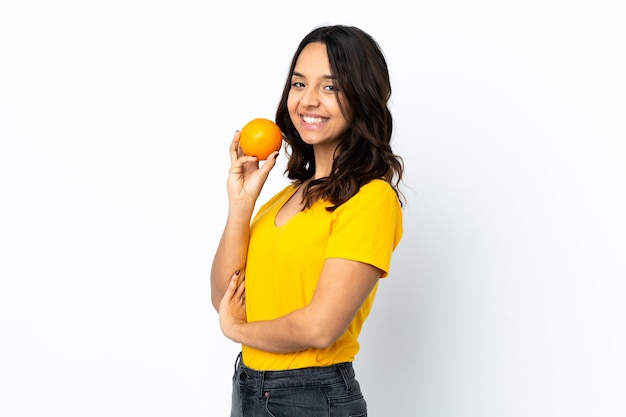 Mulher jovem em uma parede branca isolada segurando uma laranja