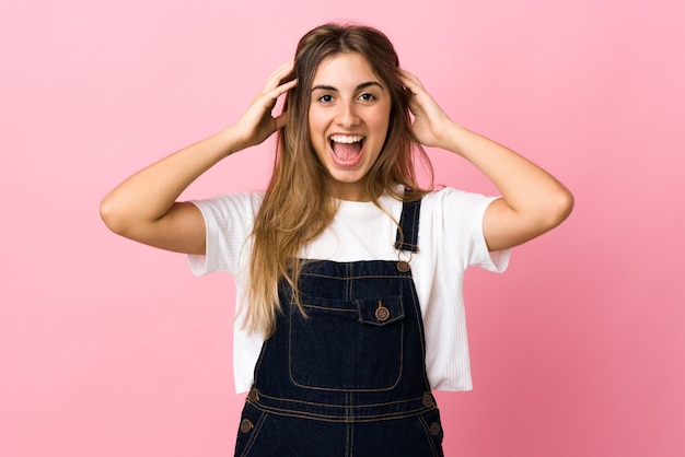 Mulher jovem em uma parede rosa isolada com expressão de surpresa