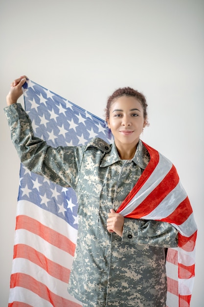 Mulher jovem em uniforme militar segurando a bandeira americana