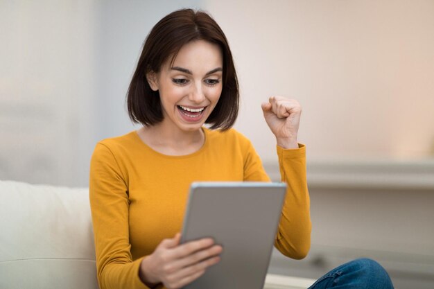 Foto mulher jovem emocional com tablet digital em sua mão gesticulando