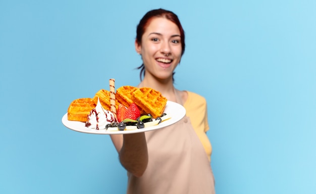 Mulher jovem empregada de padaria com waffles e bolos