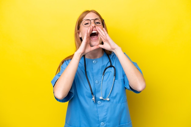 Mulher jovem enfermeira ruiva isolada em fundo amarelo gritando e anunciando algo