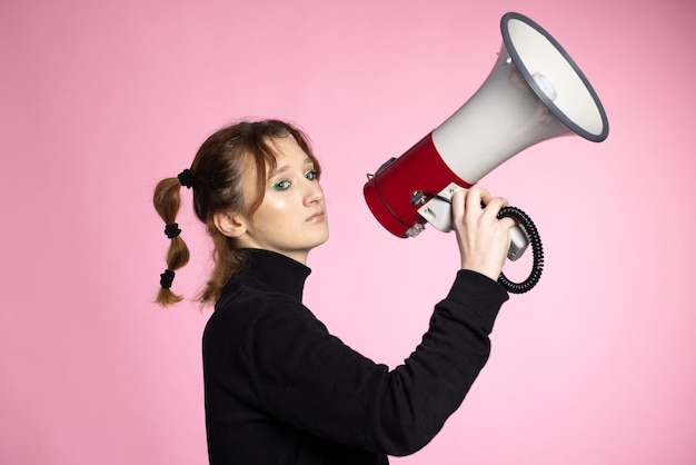 Mulher jovem engraçada gritando através do megafone jovem usando alto-falante em fundos coloridos