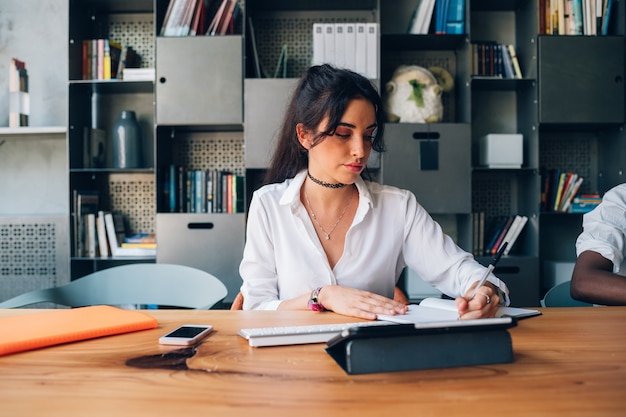 Mulher jovem, escrita, durante, reunião, em, modernos, escritório