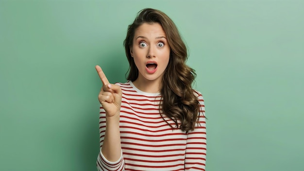 Foto mulher jovem espantada em roupas listradas apontando o dedo indicador de lado mantendo a boca bem aberta olhando