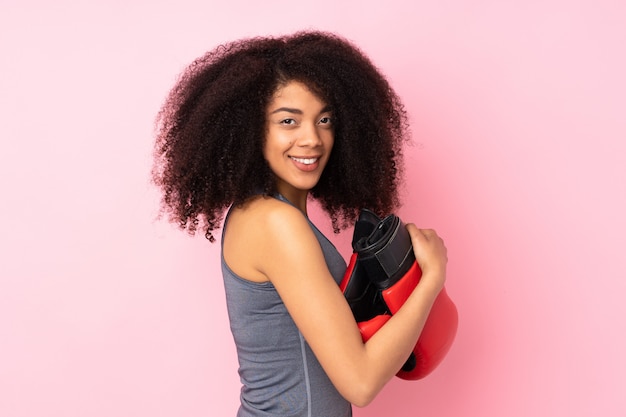 Mulher jovem esporte americano africano isolada em rosa com luvas de boxe