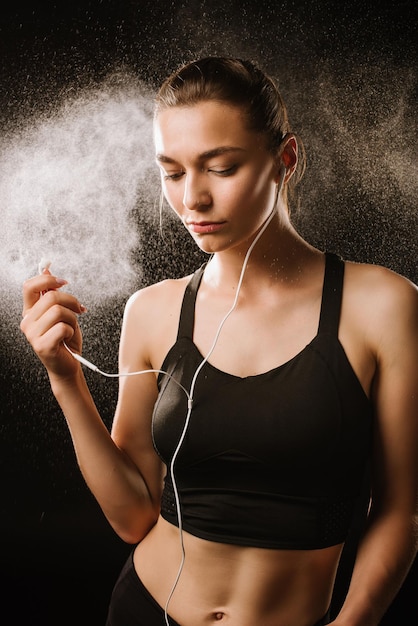 Mulher jovem esporte com fones de ouvido em fundo preto