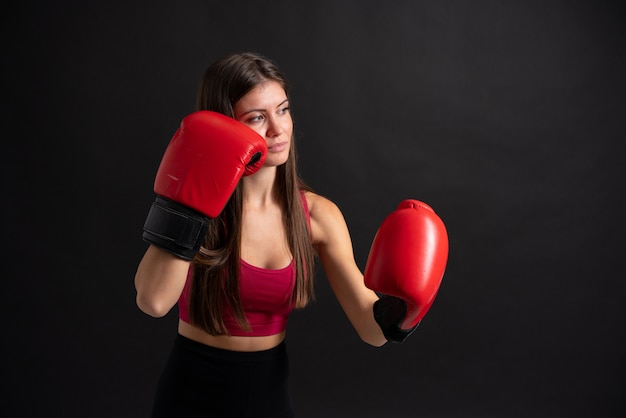 Mulher jovem esporte com luvas de boxe sobre fundo preto isolado