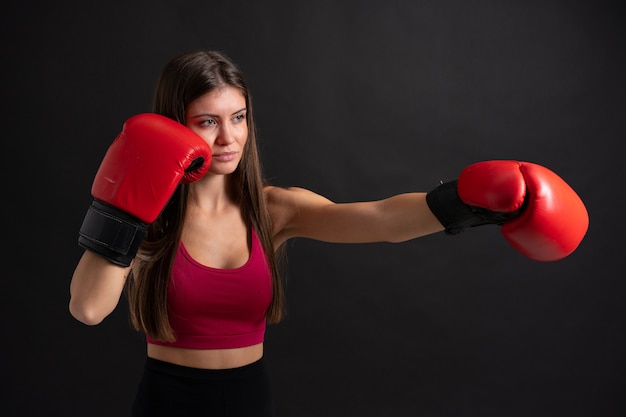 Mulher jovem esporte com luvas de boxe sobre preto isolado