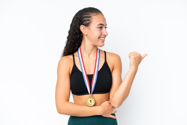 Mulher jovem esporte com medalhas isoladas no fundo branco apontando para o lado para apresentar um produto