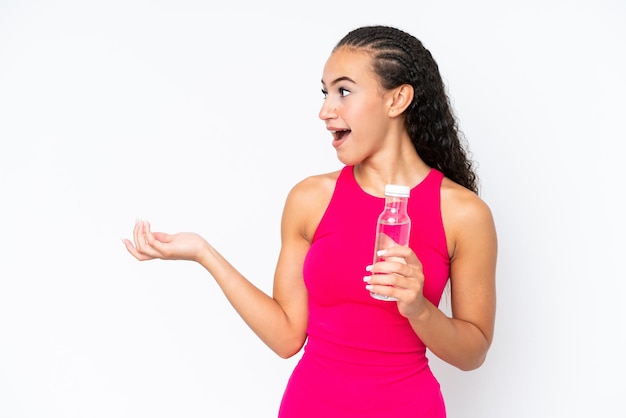 Mulher jovem esporte com uma garrafa de água isolada no branco com expressão facial de surpresa