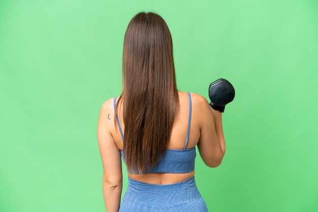 Mulher jovem esporte fazendo levantamento de peso sobre fundo croma chave isolado na posição traseira