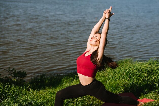 Mulher jovem esporte praticando ioga ao ar livre na margem do lago