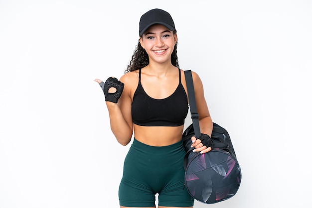 Mulher jovem esportiva com bolsa esportiva isolada no fundo branco apontando para o lado para apresentar um produto