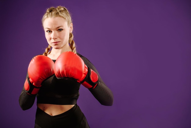 Mulher jovem esportiva usando luvas de boxe na cor de fundo