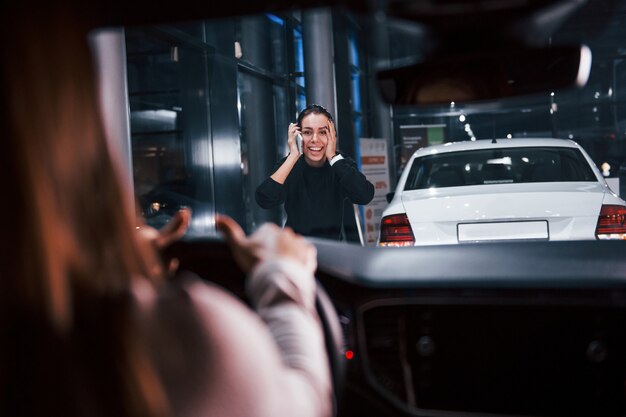 Mulher jovem está dentro de um automóvel moderno novo que segura a mão na frente dela para a garota.