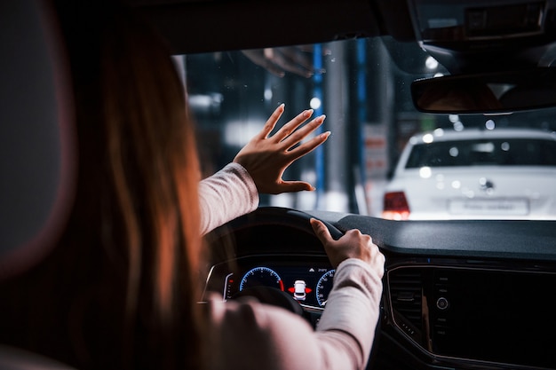 Mulher jovem está dentro de um automóvel moderno novo que segura a mão na frente dela.