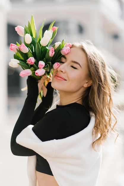 Mulher jovem está distraída de sua rotina diária desfrutando da beleza das tulipas andando pela cidade