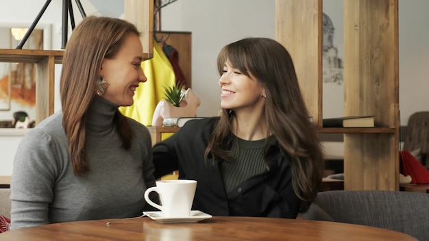 Mulher jovem está se encontrando no café para um amigo bebendo uma xícara de café