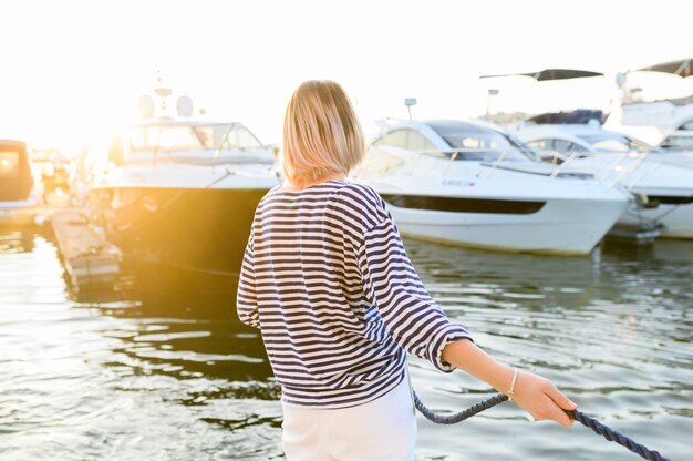 Mulher jovem estilo marinho está sentado no barco e olhando para a frente