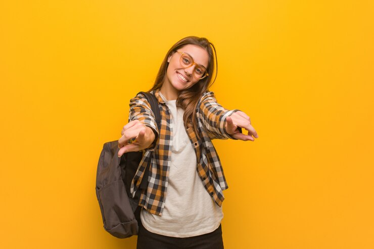 Foto mulher jovem estudante alegre e sorridente apontando