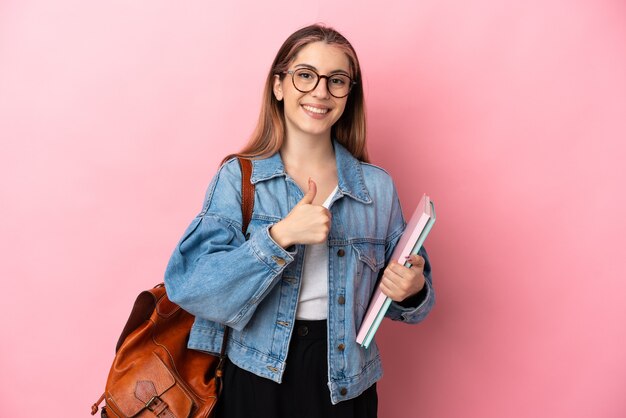 Mulher jovem estudante caucasiana isolada em rosa fazendo um gesto de polegar para cima