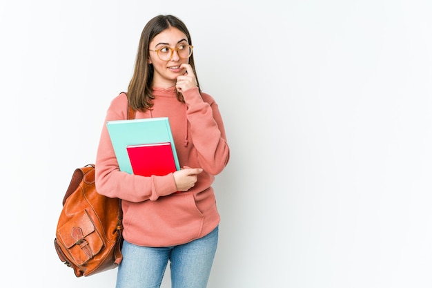 Mulher jovem estudante caucasiana isolada na parede branca relaxada pensando em algo olhando para um espaço de cópia.