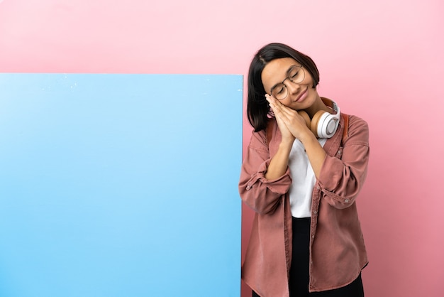 Mulher jovem estudante de raça mista com um grande banner sobre um fundo isolado fazendo gestos de dormir em expressão dorível