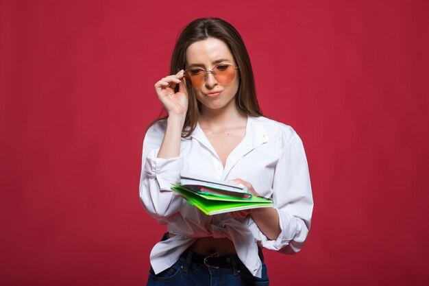 Mulher jovem estudante encaracolada usando óculos segurando livros