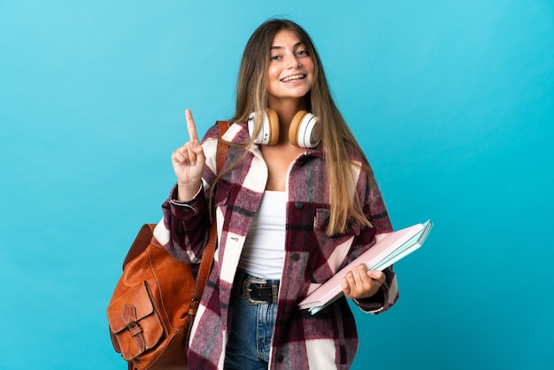 Mulher jovem estudante isolada em azul mostrando e levantando um dedo em sinal dos melhores