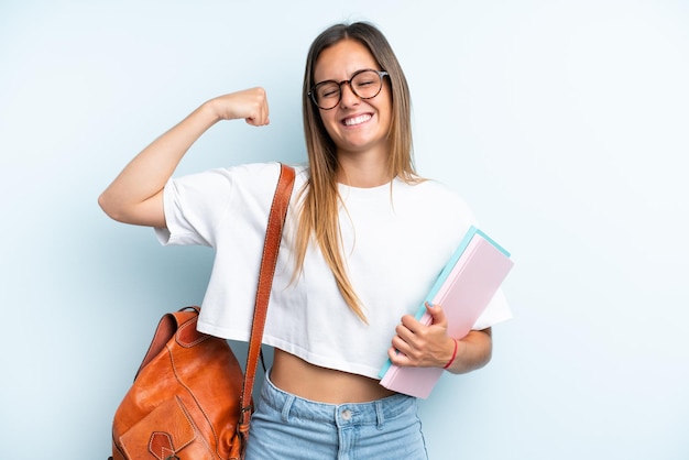 Mulher jovem estudante isolada em fundo azul fazendo um gesto forte