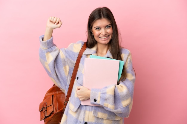 Mulher jovem estudante isolada em um fundo rosa fazendo um gesto forte