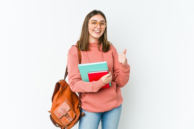 Mulher jovem estudante isolada no bakcground branco levantando ambos os polegares, sorrindo e confiante.