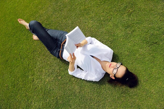 Mulher jovem estudante lendo um livro e estudando no parque