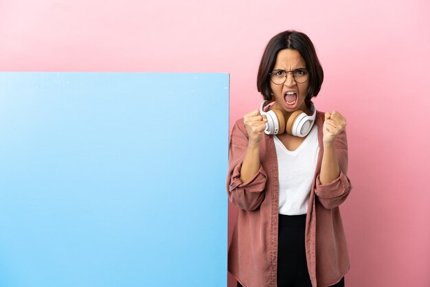 Mulher jovem estudante mestiça com um grande banner sobre um fundo isolado frustrada por uma situação ruim