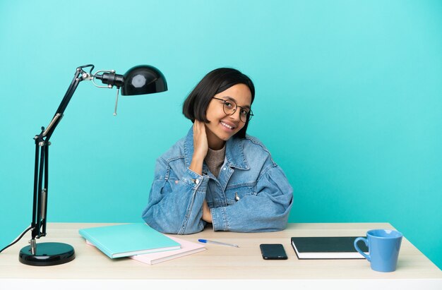 Mulher jovem estudante mestiça estudando em uma mesa rindo