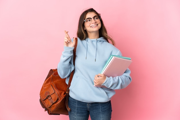 Mulher jovem estudante rosa com os dedos se cruzando e desejando o melhor